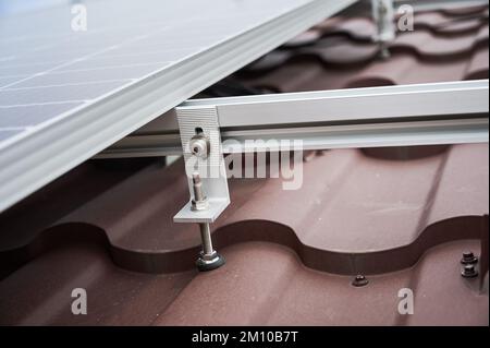 Nahaufnahme der Bergklemme des Solarpaneelsystems auf dem Hausdach. Stockfoto
