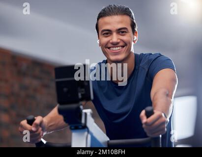 Mann, Fitness und Radfahren im Fitnessstudio für Bewegung, Training oder gesundes Herz-Kreislauf-Training. Porträt, fröhliches Lächeln oder Sport auf Heimfahrrädern oder Stockfoto