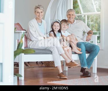 Eine wertvolle Zeit mit denen, die uns am nächsten stehen. Großeltern, die sich mit ihren Enkeln zu Hause auf dem Sofa anfreunden. Stockfoto