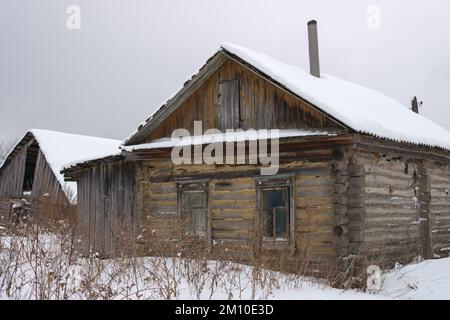 Verlassenes Holzhaus (Hütte) im russischen Dorf im Winter Stockfoto