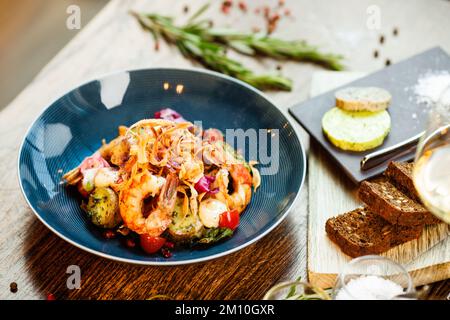 Warmer Salat mit argentinischen Königsgarnelen. Mandelkartoffel, Mini-Romana-Salat, Karotten, Kirschtomaten, Pesto, Schwarze Wurzelchips, karamellisierte Walnüsse, Rüben Stockfoto