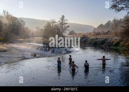 Schwimmer trotzen dem Wasser im Fluss Avon in Warleigh Weir bei Bath in Somerset heute Morgen, als die Temperaturen über Großbritannien sinken. Stockfoto