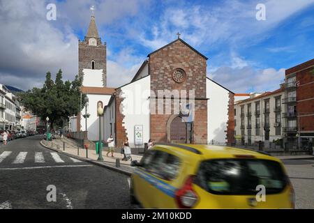 Die Kathedrale der Himmelfahrt in Sé, Funchal, Madeira, Portugal mit dem Taxi, das im Vordergrund vorbeifährt Stockfoto