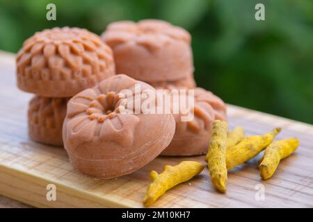 Runde Orangenseife in Form von Blumen mit Kurkuma auf grünem Hintergrund Stockfoto