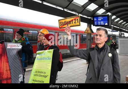 Ulm, Deutschland. 09.. Dezember 2022. Die Gegner des Milliarden Euro teuren Eisenbahnprojekts Stuttgart 21 stehen mit Plakaten am Bahnhof Ulm vor der feierlichen Eröffnung der neuen Strecke Wendlingen-Ulm. Während dieser Veranstaltung fährt von Stuttgart auf der neuen Strecke von Stuttgart nach Ulm ein besonderer EISZUG mit geladenen Gästen. Kredit: Bernd Weißbrod/dpa/Alamy Live News Stockfoto