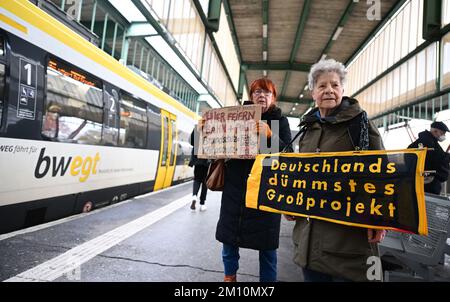 Stuttgart, Deutschland. 09.. Dezember 2022. Die Gegner des Milliarden Euro-Bahnprojekts Stuttgart 21 stehen mit Plakaten am Bahnhof Stuttgart vor der feierlichen Eröffnung der neuen Strecke Wendlingen-Ulm. Gleichzeitig fährt von Stuttgart auf der neuen Strecke von Stuttgart nach Ulm ein besonderer EISZUG mit geladenen Gästen. Kredit: Bernd Weißbrod/dpa/Alamy Live News Stockfoto