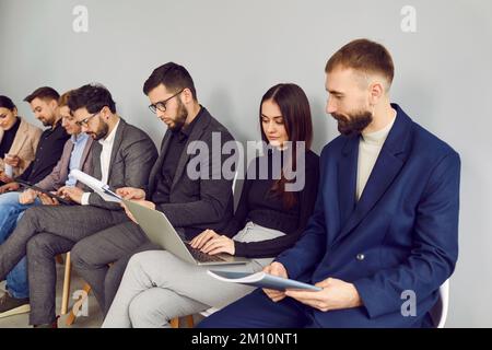 Gruppe von Geschäftsleuten, die im Büro sitzen, an ihren Projekten arbeiten und Laptops verwenden Stockfoto