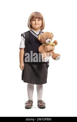 Profilaufnahme eines kleinen Schulmädchens in Uniform mit einem Teddybär isoliert auf weißem Hintergrund Stockfoto