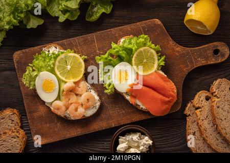 Die Toasts mit gekochten Eiern, Salat, Zitronenschleim, Garnelen und geräuchertem Lachs. Stockfoto