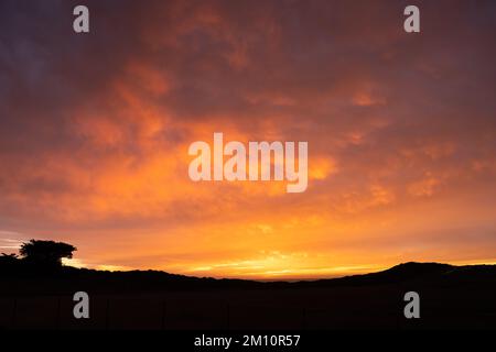 Orange und Pink bei Sonnenuntergang über California Hillside entlang der Küste von Big Sur Stockfoto