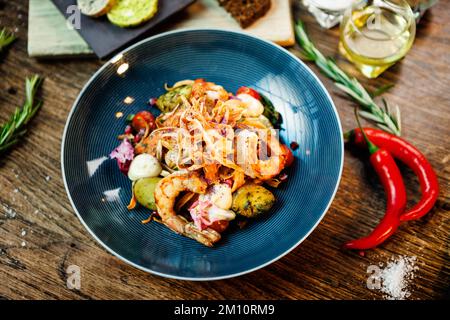 Warmer Salat mit argentinischen Königsgarnelen. Mandelkartoffel, Mini-Romana-Salat, Karotten, Kirschtomaten, Pesto, Schwarze Wurzelchips, karamellisierte Walnüsse, Rüben Stockfoto