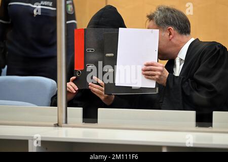 Düsseldorf, Deutschland. 09.. Dezember 2022. Der Angeklagte (l) und sein Verteidiger Andreas Wieser (r) sprechen miteinander, bevor der Prozess vor dem Oberlandesgericht beginnt, und verdecken ihre Gesichter mit Ordnern. Der 17-jährige Student steht vor Gericht, weil er einen rechtsextremistischen Terroranschlag auf eine Highschool in Essen vorbereitet hat. Kredit: Federico Gambarini/dpa/Alamy Live News Stockfoto