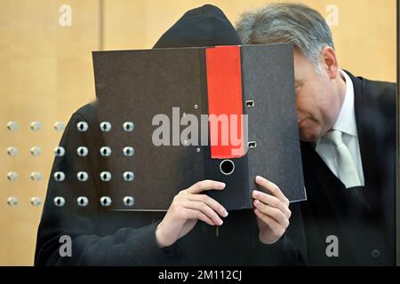 Düsseldorf, Deutschland. 09.. Dezember 2022. Der Beklagte (l) verdeckt sein Gesicht mit einer Akte, während er vor Beginn des Verfahrens vor dem Oberlandgericht mit seinem Verteidiger Andreas Wieser (r) sprach. Der 17-jährige Student steht vor Gericht, weil er einen rechtsextremistischen Terroranschlag auf eine Highschool in Essen vorbereitet hat. Kredit: Federico Gambarini/dpa/Alamy Live News Stockfoto