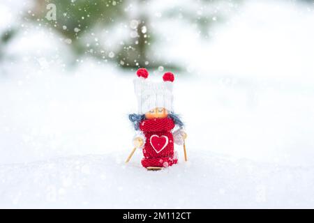 Skifahrerin mit Schal und Strickmütze Elfenspielzeug auf Skiern in verschneiter Landschaft Neujahr, Frohe Weihnachten Grußkarte Winter Frohe Neujahrskarte Hallo Dezember, Januar, Februar. Stockfoto