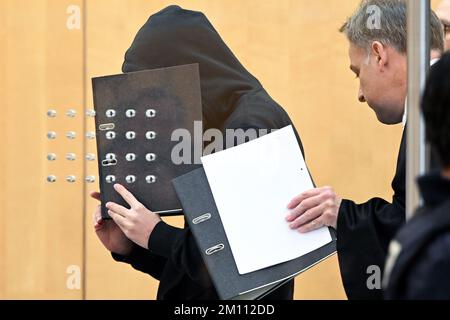 Düsseldorf, Deutschland. 09.. Dezember 2022. Der Angeklagte (l) verdeckt sein Gesicht mit einer Akte, wenn er zu Beginn des Prozesses mit seinem Verteidiger Andreas Wieser (r) in einer Halle beim Obersten Landesgericht eintrifft. Der 17-jährige Student steht vor Gericht, weil er einen rechtsextremistischen Terroranschlag auf eine Highschool in Essen vorbereitet hat. Kredit: Federico Gambarini/dpa/Alamy Live News Stockfoto