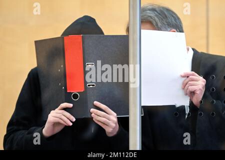 Düsseldorf, Deutschland. 09.. Dezember 2022. Der Angeklagte (l) und sein Verteidiger Andreas Wieser (r) sprechen miteinander, bevor der Prozess vor dem Oberlandesgericht beginnt, und verdecken ihre Gesichter mit Ordnern. Der 17-jährige Student steht vor Gericht, weil er einen rechtsextremistischen Terroranschlag auf eine Highschool in Essen vorbereitet hat. Kredit: Federico Gambarini/dpa/Alamy Live News Stockfoto