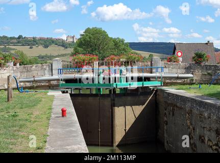 Schiffsschleuse im Burgund-Kanal in Vandenesse en Auxois, Frankreich. Auf einem Hügel befindet sich das Schloss Chateauneuf Stockfoto