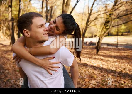 Big and strong guy rides his slender girlfriend on backs Stockfoto