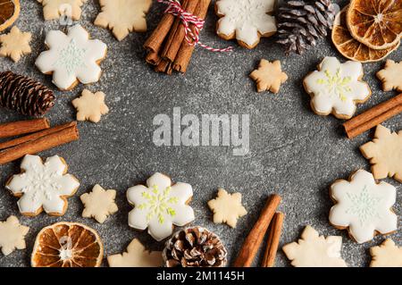 Weihnachten Lebkuchen. Köstliche Lebkekse, Zapfen, getrocknete Orangen und Zimtstangen auf grauem Betonhintergrund. Winterkomposition. Großartig Stockfoto