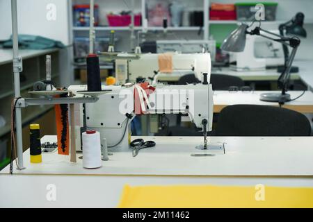 Moderne Nähmaschinen auf den Tischen in der Werkstatt Stockfoto