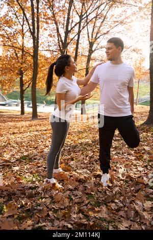 Die junge Frau macht ein Aufwärmen mit ihrem Freund im Park Stockfoto