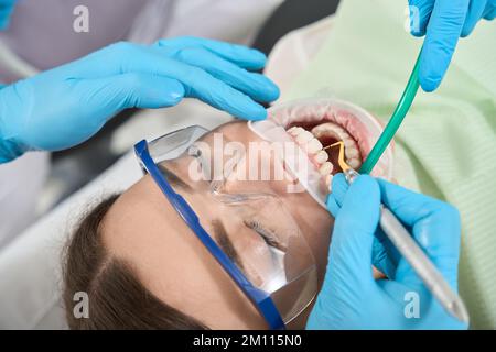 Der Fachzahnarzt, der an einer jungen Frau eine Zahnskala durchführt Stockfoto