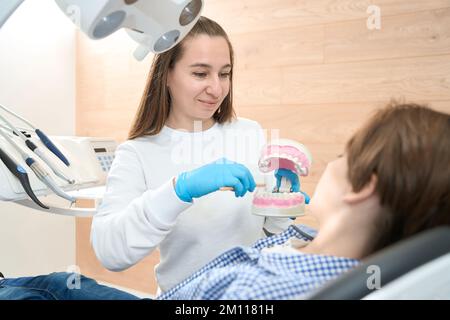 Frauenhygienikerin hält Modellgebiss mit Zahnspange in den Händen Stockfoto