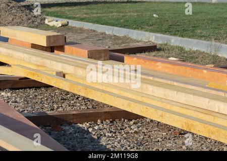Holzmaterial auf der Baustelle im November, Nahaufnahme, selektiver Fokus. Holzbretter sind in Reihen gestapelt und liegen auf dem Boden. Tafeln für Konstruktionen Stockfoto