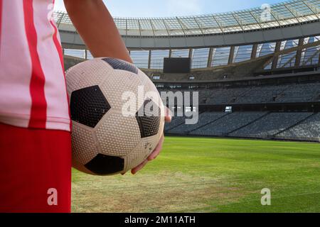 Mitte des Spielers, der an sonnigen Tagen Fußball im Stadion hält, Kopierraum. Fußball, Sportler, Sportler, Sport, Wettkampfsport, Spiel, Geschick. Stockfoto