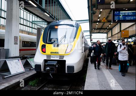 Stuttgart, Deutschland. 09.. Dezember 2022. Ein SWEG-Zug, der nicht bestiegen werden kann, steht auf dem Gleis. Die Passagiere stehen davor. Triebwerkfahrer von GDL kündigten neue Streiks bei der Eisenbahngesellschaft SWEG an. Kredit: Ilkay Karakurt/dpa/Alamy Live News Stockfoto