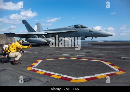 Philippinensee, Vereinigte Staaten. 09.. Dezember 2022. EIN US-AMERIKANISCHER Navy F/A-18E Super Hornet Fighter Aircraft, das an das Royal Maces of Strike Fighter Squadron 27 angeschlossen ist, erhält grünes Licht für den Start vom Cockpit des Flugzeugträgers der Nimitz-Klasse USS Ronald Reagan, der am 9. Dezember 2022 auf der Philippine Sea eingesetzt wird. Kredit: MC3 Dallas Snider/USA Navy/Alamy Live News Stockfoto