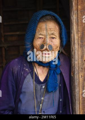 Ziro, Arunachal Pradesh, Indien - 02 24 2009 : Porträt der alten Apatani-Stammesfrau mit traditionellen Gesichts-Tattoos und Nasenstöpseln mit blauem Schal Stockfoto