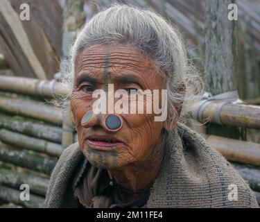Ziro, Arunachal Pradesh, Indien - 03 04 2014 : Porträt der alten Apatani-Stammesfrau mit traditionellen Gesichtstätowierungen und Nasenstöpseln im Freien Stockfoto