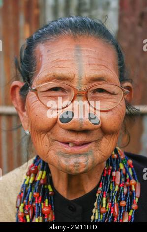 Ziro, Arunachal Pradesh, Indien - 03 04 2014 : Porträt einer lächelnden alten Apatani-Stammesfrau mit Gesichtszettel und Brillenstöpseln Stockfoto