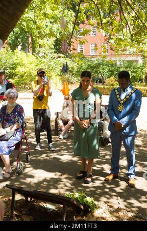 Bürgermeister von Camden, Cllr Nasim Ali, beobachtet eine Stille in der Nähe des Kirschbaums, der zum Gedenken an die Opfer von Hiroshima während einer Veranstaltung in London gepflanzt wurde. Stockfoto