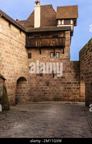 Bruchstück des Hofes der Kaiserlichen Burg und Steinmauern mit Gehwegen, einem Turm und einem Balkon. Nürnberg, Bayern, Deutschland. Stockfoto