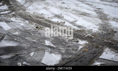 Spuren von Autoreifen im Schnee auf Asphalt. Straßenhintergrund im Winter Stockfoto