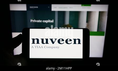 Person, die ein Mobiltelefon mit dem Logo der US-amerikanischen Vermögensverwaltungsgesellschaft Nuveen auf dem Bildschirm vor der Unternehmenswebseite hält. Konzentrieren Sie sich auf das Display des Telefons. Stockfoto