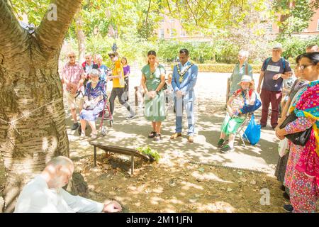 Bürgermeister von Camden, Cllr Nasim Ali, beobachtet eine Stille in der Nähe des Kirschbaums, der zum Gedenken an die Opfer von Hiroshima während einer Veranstaltung in London gepflanzt wurde. Stockfoto