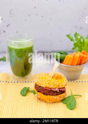 Grüner köstlicher Burger mit Spinat-Smoothie auf Betonhintergrund Stockfoto