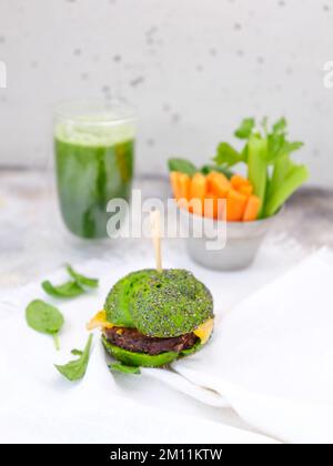 Grüner köstlicher Burger mit Spinat-Smoothie auf Betonhintergrund Stockfoto