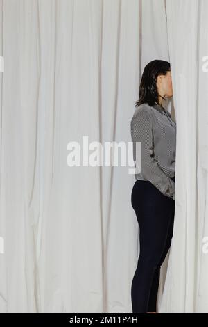 Seitenansicht einer Frau mit Gesicht hinter dem Vorhang Stockfoto