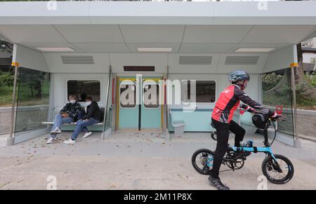 Leute, die in einem Simulations-MTR-Abteil am Lam Tsuen River in Tai Po sitzen. Sitze und Türen der Mid-Life Renoved Züge (MLR), die im Mai von der MTR East Rail Line zurückgezogen wurden, wurden renoviert und in einem Sitzbereich am Fluss Lam Tsuen in Tai Po zu einem Regenschutz gebaut. 05DEC22 SCMP/Gelee-Tse Stockfoto