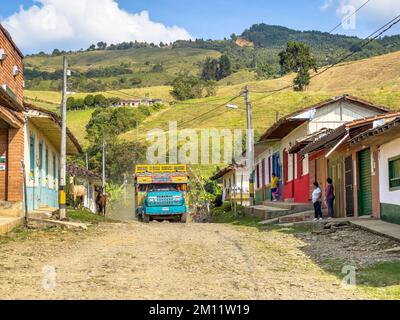 Südamerika, Kolumbien, Departamento Antioquia, kolumbianische Anden, typischer Bus „Chiva“ auf einer staubigen Straße in einem kleinen Andendorf Stockfoto