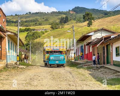 Südamerika, Kolumbien, Departamento Antioquia, kolumbianische Anden, typischer Bus „Chiva“ auf einer staubigen Straße in einem kleinen Andendorf Stockfoto