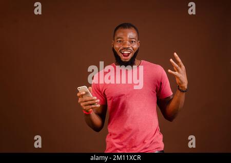 Ein gut aussehender afroamerikanischer Mann mit einem Telefon auf braunem Hintergrund Stockfoto