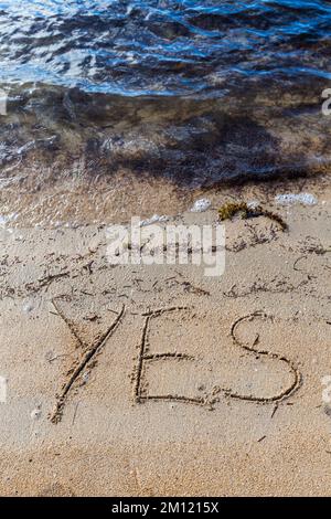 Ja - wie eine Nachricht mit einem Finger im Sand geschrieben an einem Strand mit Wellen und blauem Ozean auf Mauritius Island, Afrika, Draufsicht, niemand Stockfoto
