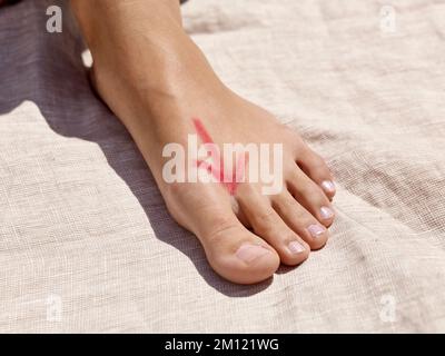 Barfußgehen - Nahaufnahme eines Frauenfußes mit einem reflexzonenförmigen Pfeil auf der Rückseite des Fußes Stockfoto