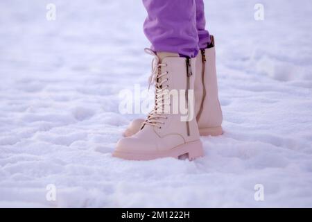 Füsse in Winterstiefeln. Mit Winterstiefeln auf Schnee spazieren gehen. Nahaufnahme. Selektiver Fokus Stockfoto