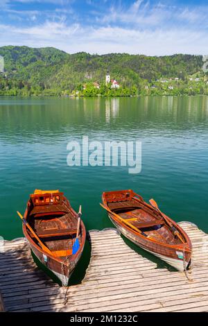 Blick auf zwei typische Boote des Bleder Sees mit Kirche und Insel. Bled, Oberkarniola, Slowenien. Stockfoto